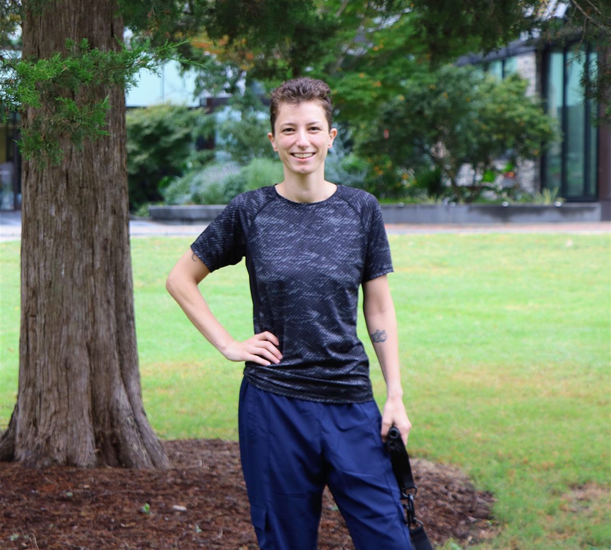 Dion Philpot smiling, standing on a lawn beside a tree